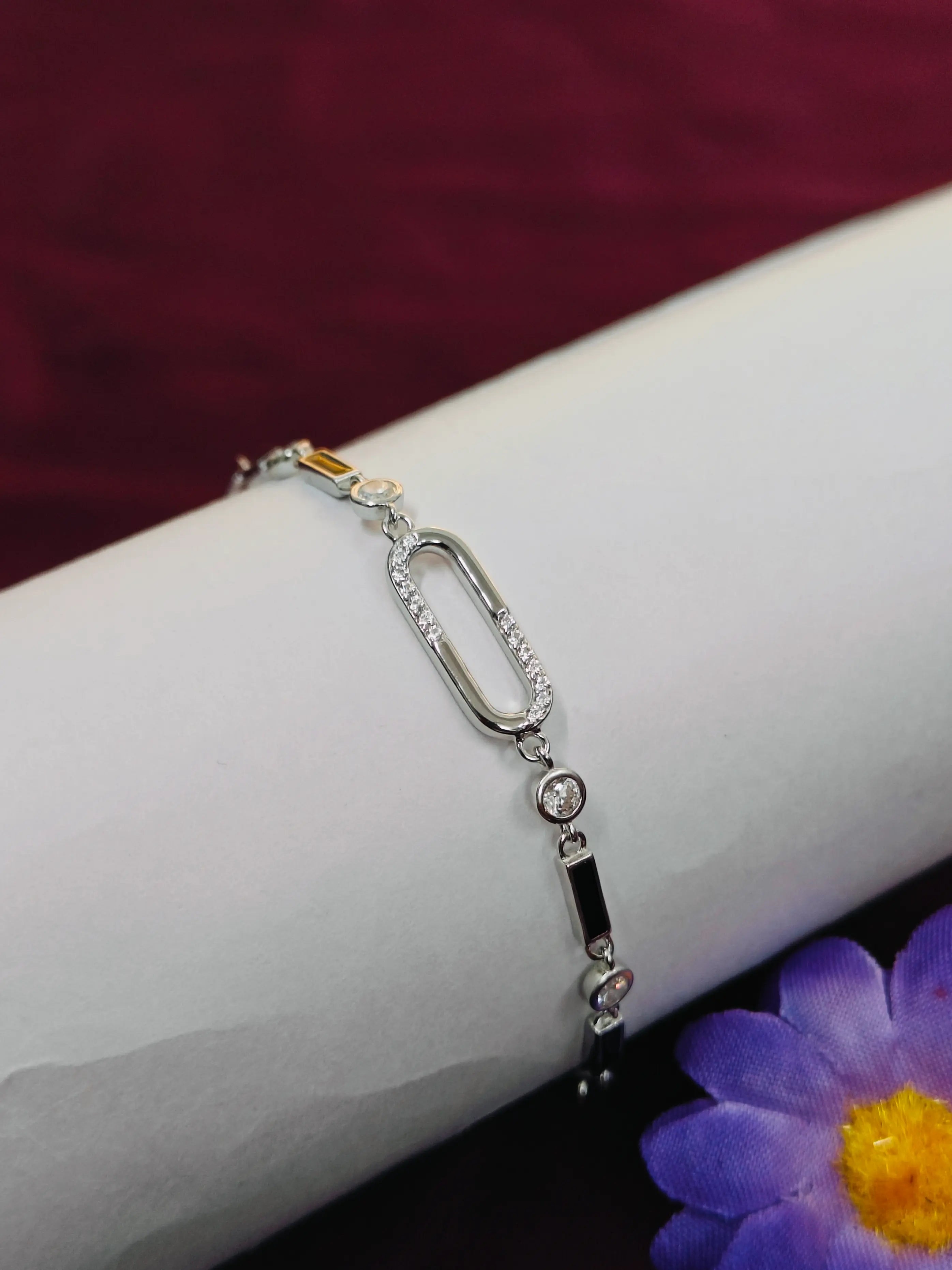 Silver bracelet on a wrist with a blurred purple flower in the background